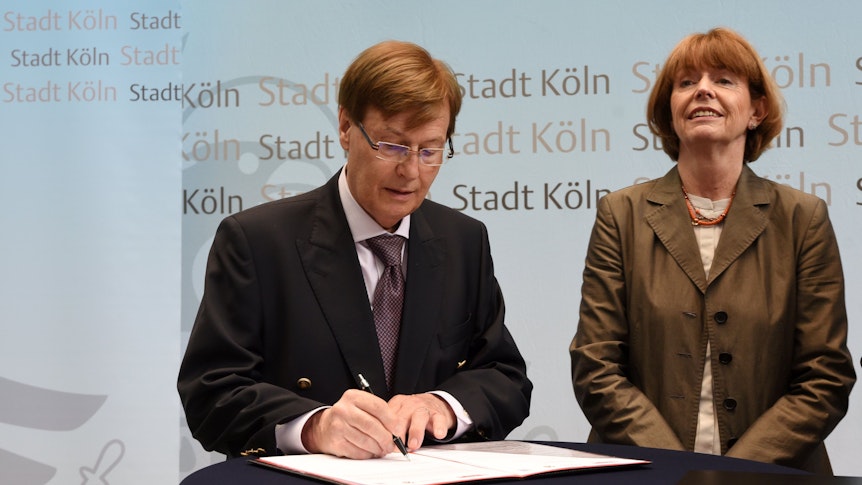NRW-Justizminister Peter Biesenbach und Kölns OB Henriette Reker unterzeichnen ein Papier.