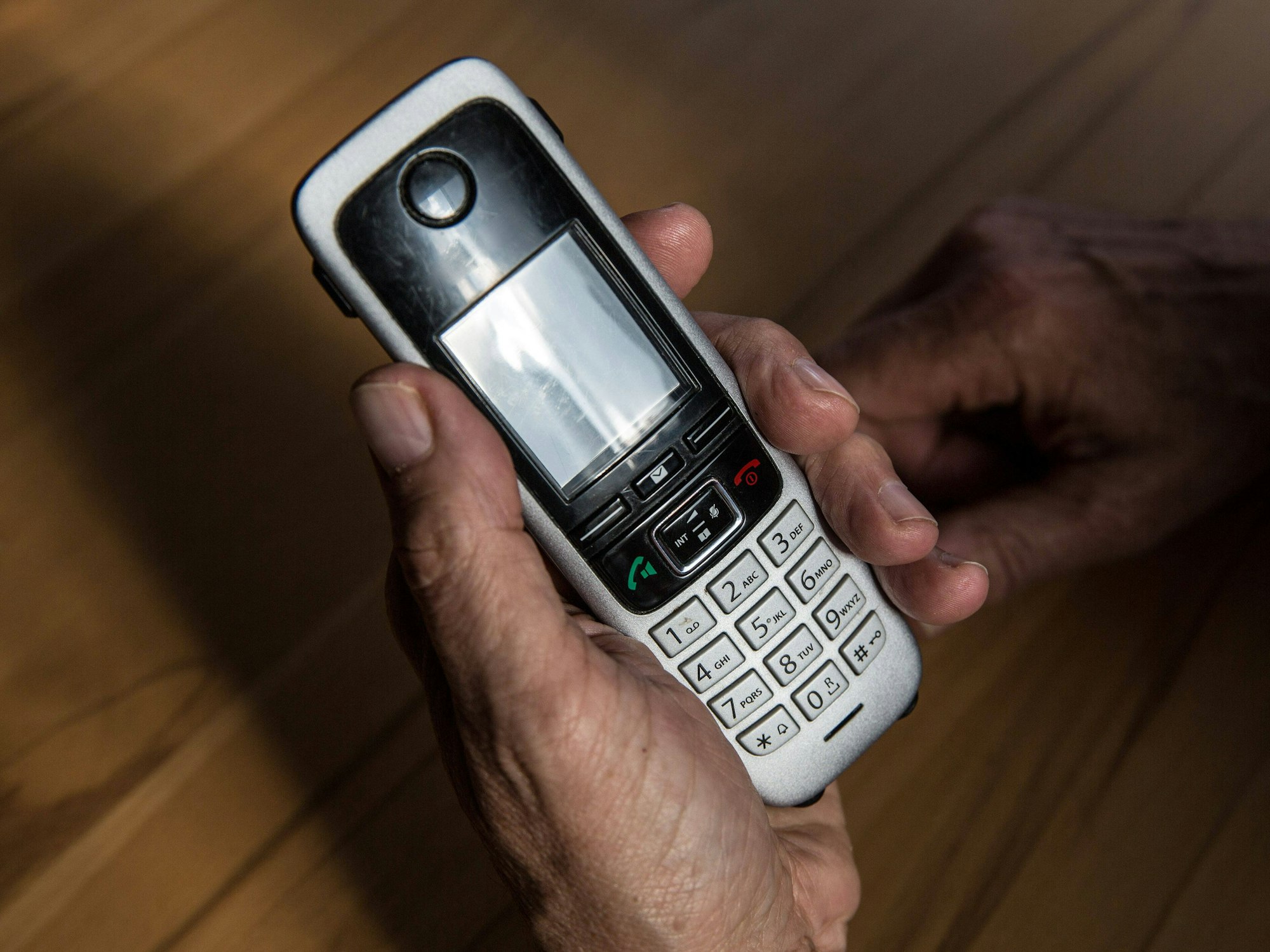 Symbolbild: Ein älterer Mann hält am 29. April 2021 ein kabelloses Festnetztelefon in der Hand.