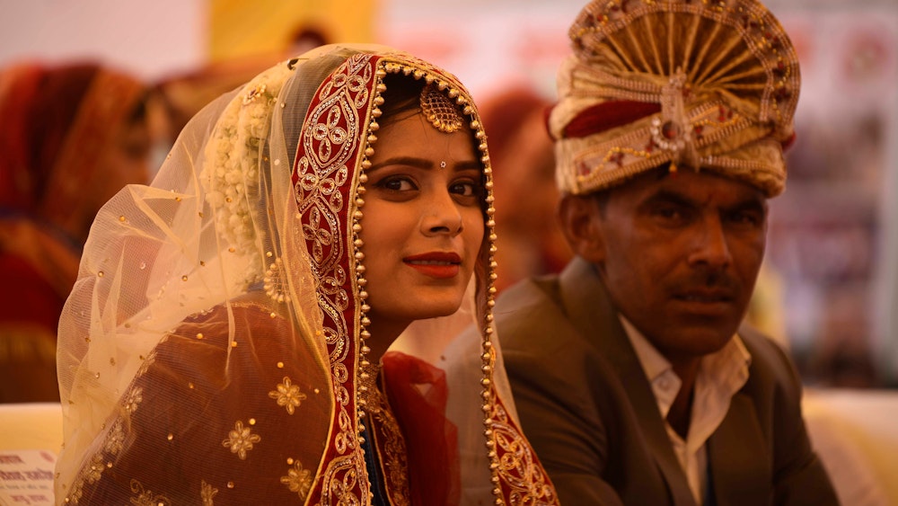 Braut und Bräutigam in traditioneller Kleidung bei einer Massenhochzeit in Indien im April 2022