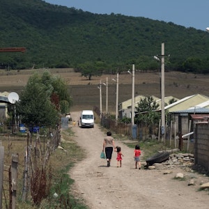 Eine Frau spaziert am 28.07.2018 mit ihren Kindern durch die staubigen Straßen des georgischen Flüchtlingsdorfes Freseti an der Grenze zu Südossetien. Die Separatistenregion will über den Beitritt zur russischen Föderation abstimmen lassen.