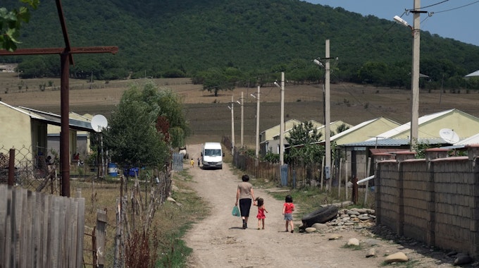 Eine Frau spaziert am 28.07.2018 mit ihren Kindern durch die staubigen Straßen des georgischen Flüchtlingsdorfes Freseti an der Grenze zu Südossetien. Die Separatistenregion will über den Beitritt zur russischen Föderation abstimmen lassen.