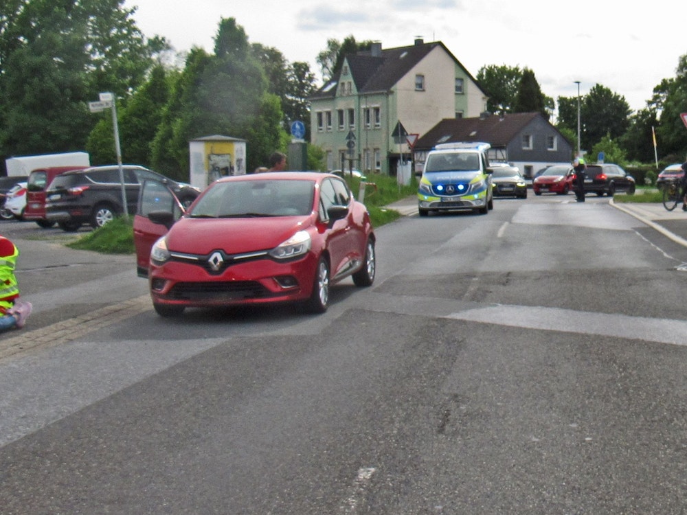 Ein roter Renault Clio steht nach einem Unfall auf der Straße – dahinter ein Polizeifahrzeug.