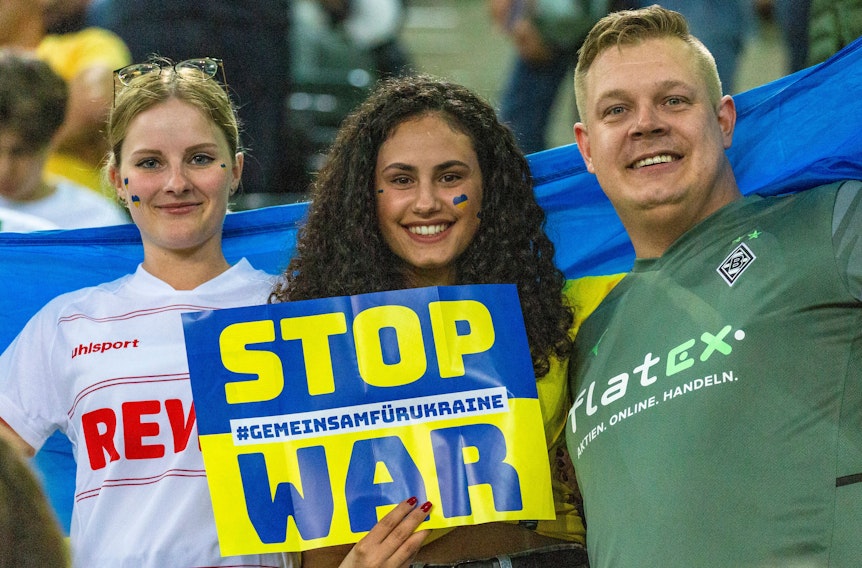 „Stop War“-Aufforderung von ukrainischen und deutschen Zuschauerinnen und Zuschauer während des Benefizspiels von Borussia Mönchengladbach gegen die Nationalmannschaft der Ukraine am 11. Mai 2022 im Borussia-Park. Auch eine Anhängerin des 1. FC Köln ist dabei.