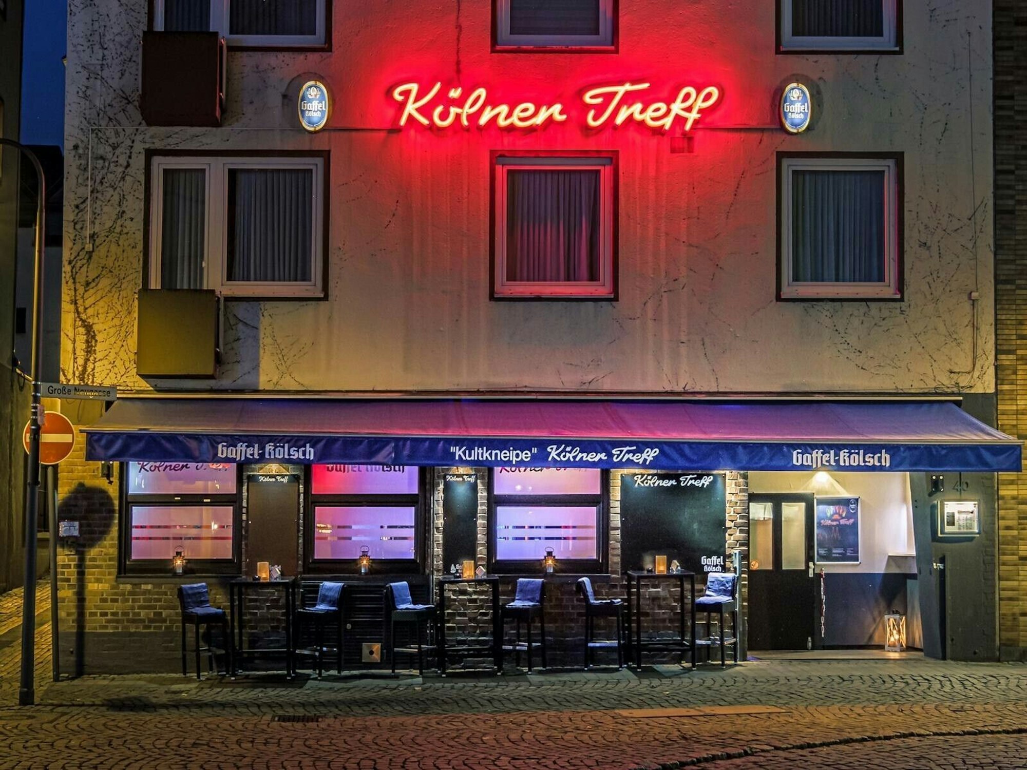 Der „Kölner Treff“ in der Große Neugasse in der Kölner Altstadt. Über dem Eingang leuchtet in Rot der Kneipenname.