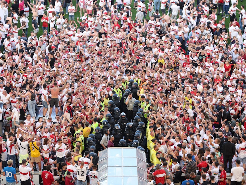 Ordner und Polizisten sichern den Spielertunnel während Stuttgart-Fans den Klassenerhalt feiern.