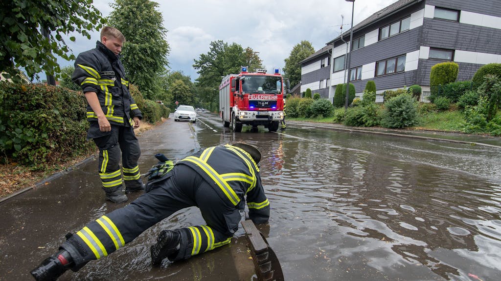 Nach dem Bilderbuchwochenende warnt der Deutsche Wetterdienst vor einem Wetter-Umschwung. Starkregen und Überflutungen sind möglich. Dasundatierte Symbolbild aus NRW zeigt Feuerwehrleute nach Starkregen an einer überfluteten Straße.
