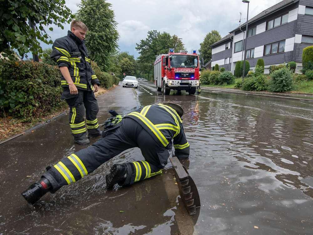 Nach dem Bilderbuchwochenende warnt der Deutsche Wetterdienst vor einem Wetter-Umschwung. Starkregen und Überflutungen sind möglich. Dasundatierte Symbolbild aus NRW zeigt Feuerwehrleute nach Starkregen an einer überfluteten Straße.