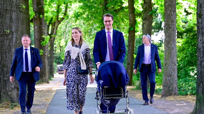 Hendrik Wüst spaziert mit seiner Familie durch einen Park.