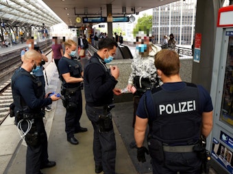 Beamte der Polizei kontrollieren eine Person am Kölner Hauptbahnhof.
