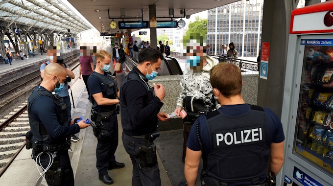 Kräfte von Polizei, Ordnungsamt und DB Sicherheit kontrollieren auf einem Bahnsteig des Kölner Hauptbahnhofs einen Mann.