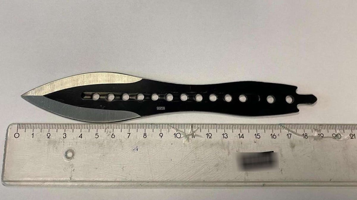 Das schwarze Wurfmesser liegt neben einem Lineal und hat eine knapp acht Zentimeter lange Klinge.