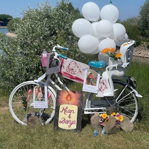 An einem Fahrrad samt Kindersitz sind Luftballon, Bilder und Fotos befestigt. Auf einem Schild steht „Kian und Derya“.
