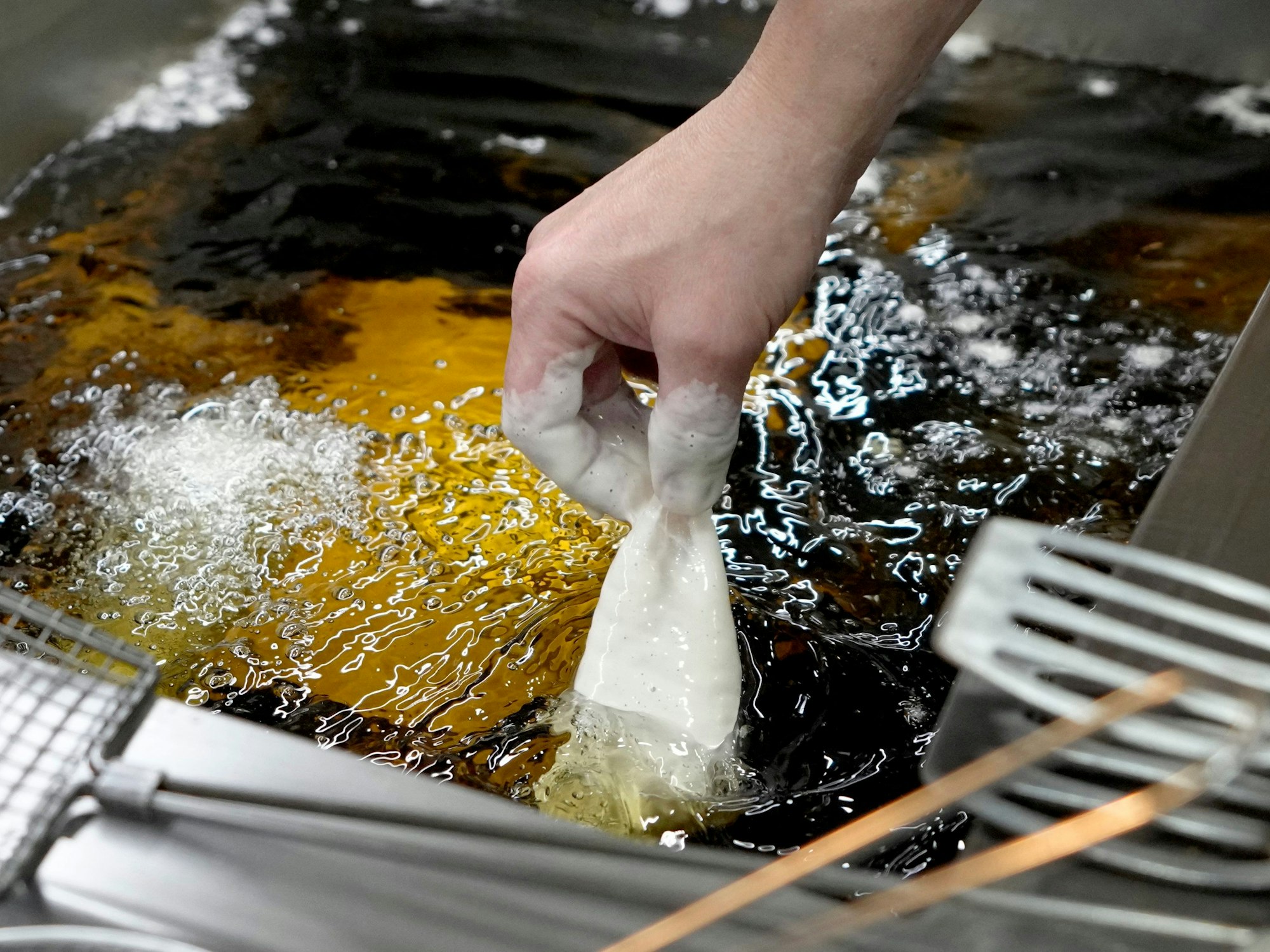 Panierter Fisch wird in heißes Sonnenblumenöl gelegt.