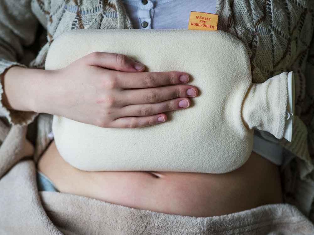 Eine junge Frau hält sich am 06.04.2013 in Bamberg (Bayern) wegen Bauchschmerzen eine Wärmflasche auf den Bauch.