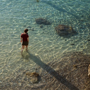 Eine Frau spaziert am 23. Mai 2021 am Strand von Limeni, einem kleinen Fischerhafen auf der Halbinsel Mani in Griechenland.