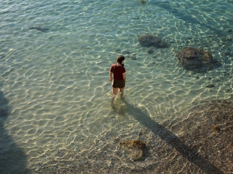 Eine Frau spaziert am 23. Mai 2021 am Strand von Limeni, einem kleinen Fischerhafen auf der Halbinsel Mani in Griechenland.