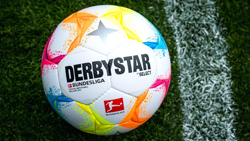 Der neue Bundesliga-Spielball mit vielen farblichen Details liegt auf Fußball-Rasen.