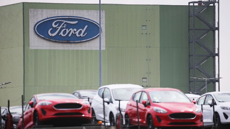 Neu gebaute Autos stehen auf Lastwagen vor dem Ford Werk.