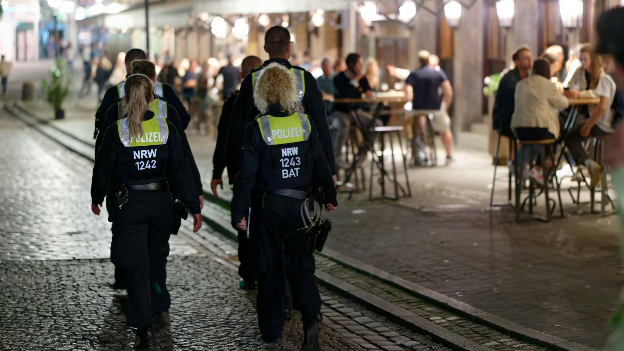 Polizisten im Dienst patrouillieren nach Mitternacht in der Altstadt zwischen Feiernden.