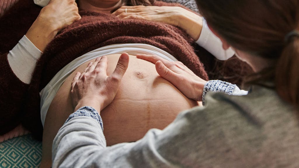 Das undatierte Symbolfoto zeigt eine Schwangere, deren Bauch von einer Hebamme abgetastet wird.