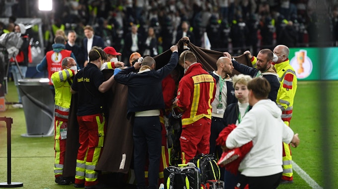 Medizinische Angestellte schirmen den Mann ab, der beim DFB-Pokal-Finale eine Herzattacke erlitten hatte