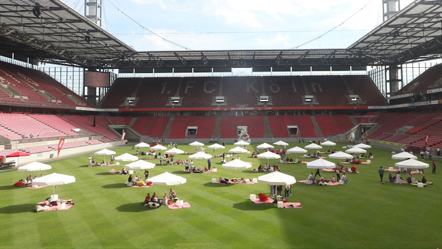 Sonnenschirme stehen nebeneinander auf einem Fußballfeld.