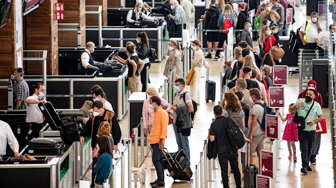 Reisende stehen am Flughafen am Check-In-Schalter.