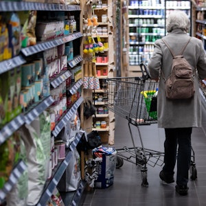 Eine Frau geht mit ihrem Einkaufswagen durch einen Supermarkt. Die hohen Preise von Lebensmitteln zwingen viele Menschen dazu, ihr Einkaufsverhalten zu ändern.