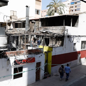 Menschen gehen nach einem Brand am Restaurant «Why Not Mallorca?» vorbei. Die Polizei hat auf Mallorca 13 deutsche Urlauber festgenommen, weil sie den Brand ausgelöst haben sollen.