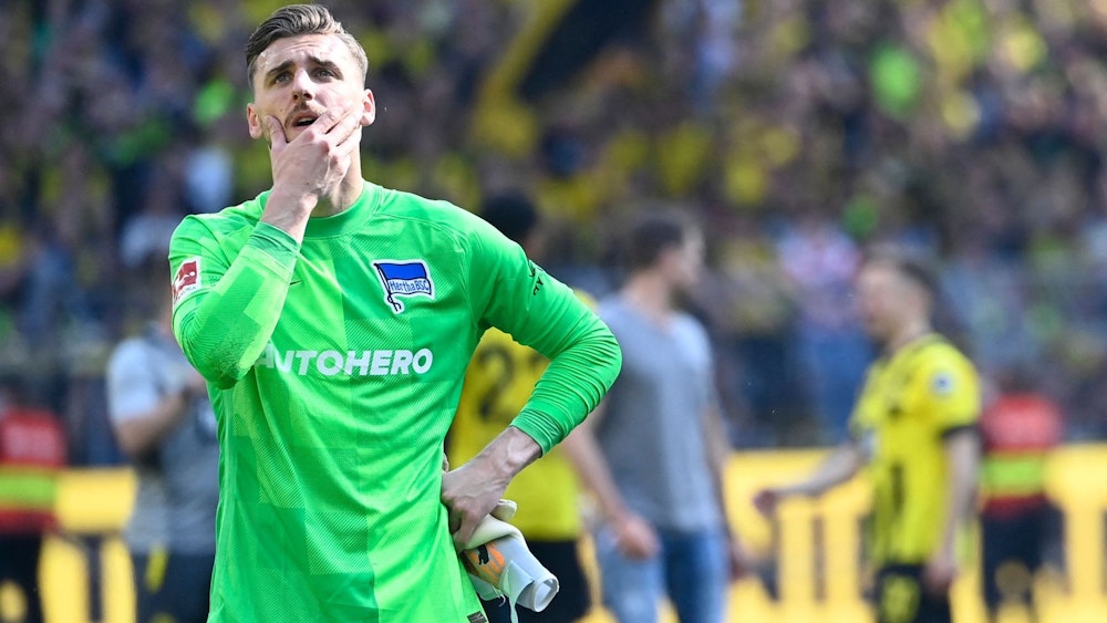 Marcel Lotka steht nach der Niederlage von Hertha BSC bei Borussia Dortmund enttäuscht vor der Berliner Fankurve
