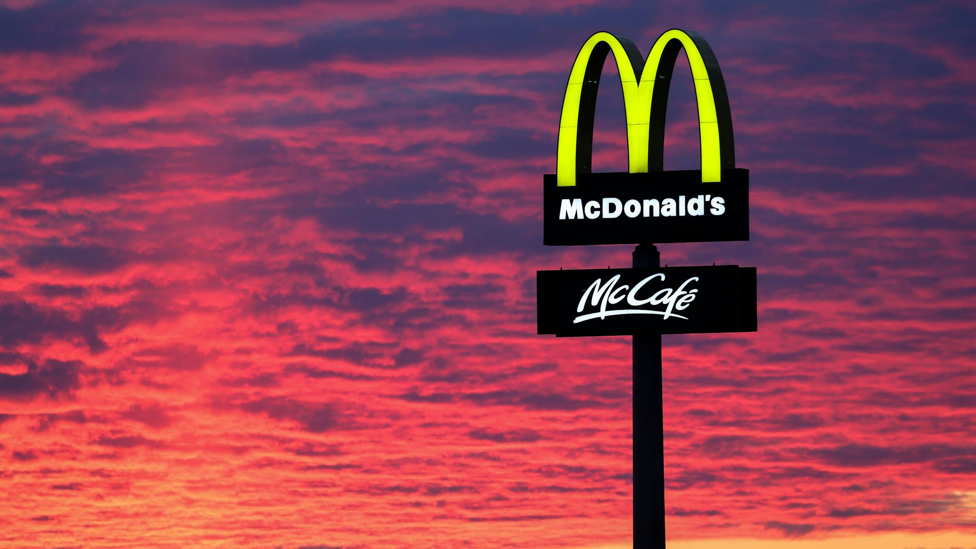 Der Abendhimmel leuchtet rötlich am30. November 2020 hinter einem McDonalds-Logo.