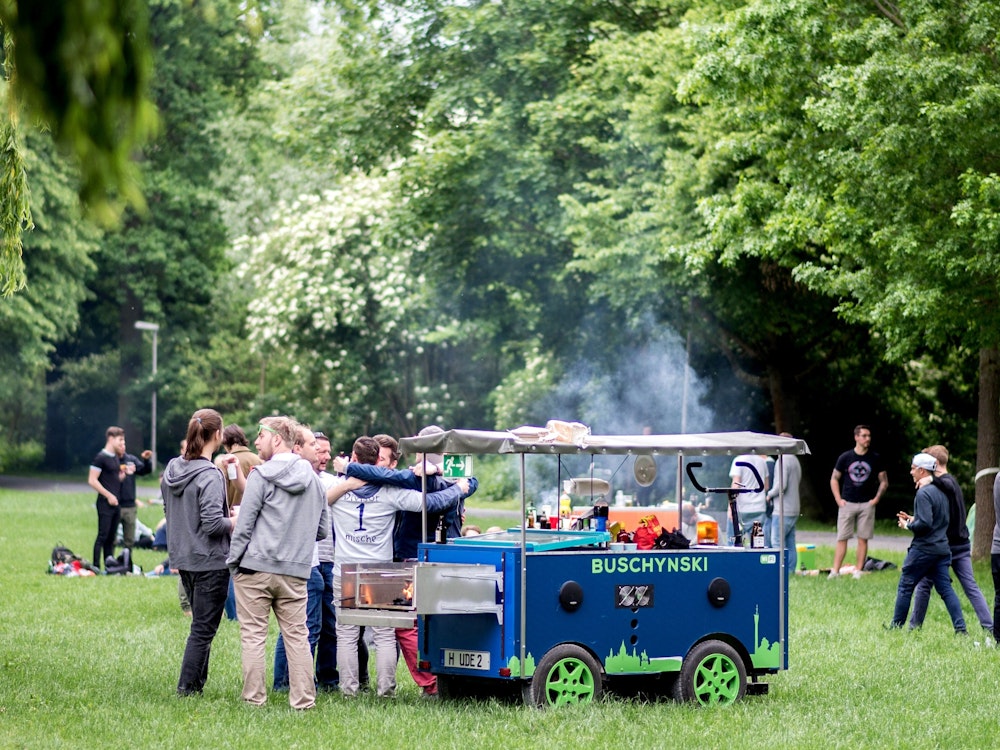Eine Gruppe junger Männer feiert bei einer Vatertagstour mit einem umgebauten Bollerwagen.