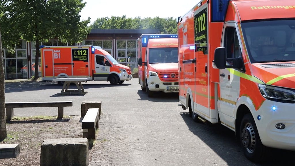 Einsatzfahrzeuge vom Rettungsdienst Bielefeld stehen vor der Schule.&nbsp;