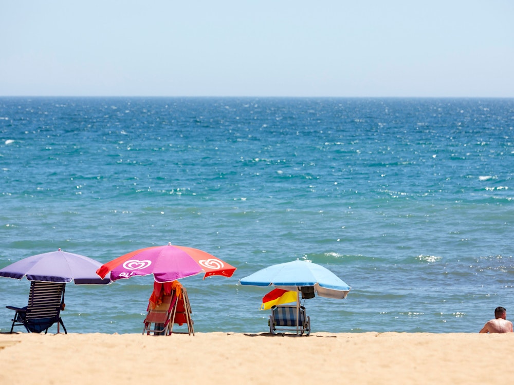 Ein paar Sonnenliegen- und Schirme stehen am 29. Juni 2021 am Strand von Portugal.