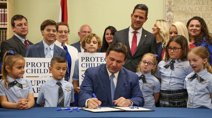Gouverneur Ron DeSantis unterzeichnet ein Gesetz in Florida. Um ihn stehen mehrere Schülerinnen und Schüler.