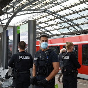 Drei Einsatzkräfte stehen an einem Gleis im Kölner Hauptbahnhof.