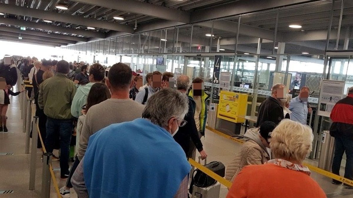 Menschen warten in einer langen Schlange vor der Sicherheitskontrolle im Flughafen Köln/Bonn.