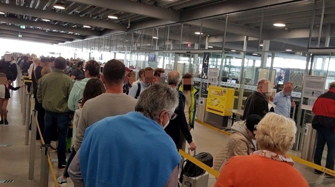 Menschen warten in einer langen Schlange vor der Sicherheitskontrolle im Flughafen Köln/Bonn.
