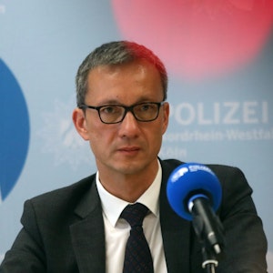 Der Kölner Polizeipräsident Falk Schnabel sitzt auf einem Podium vor einem Mikrofon.