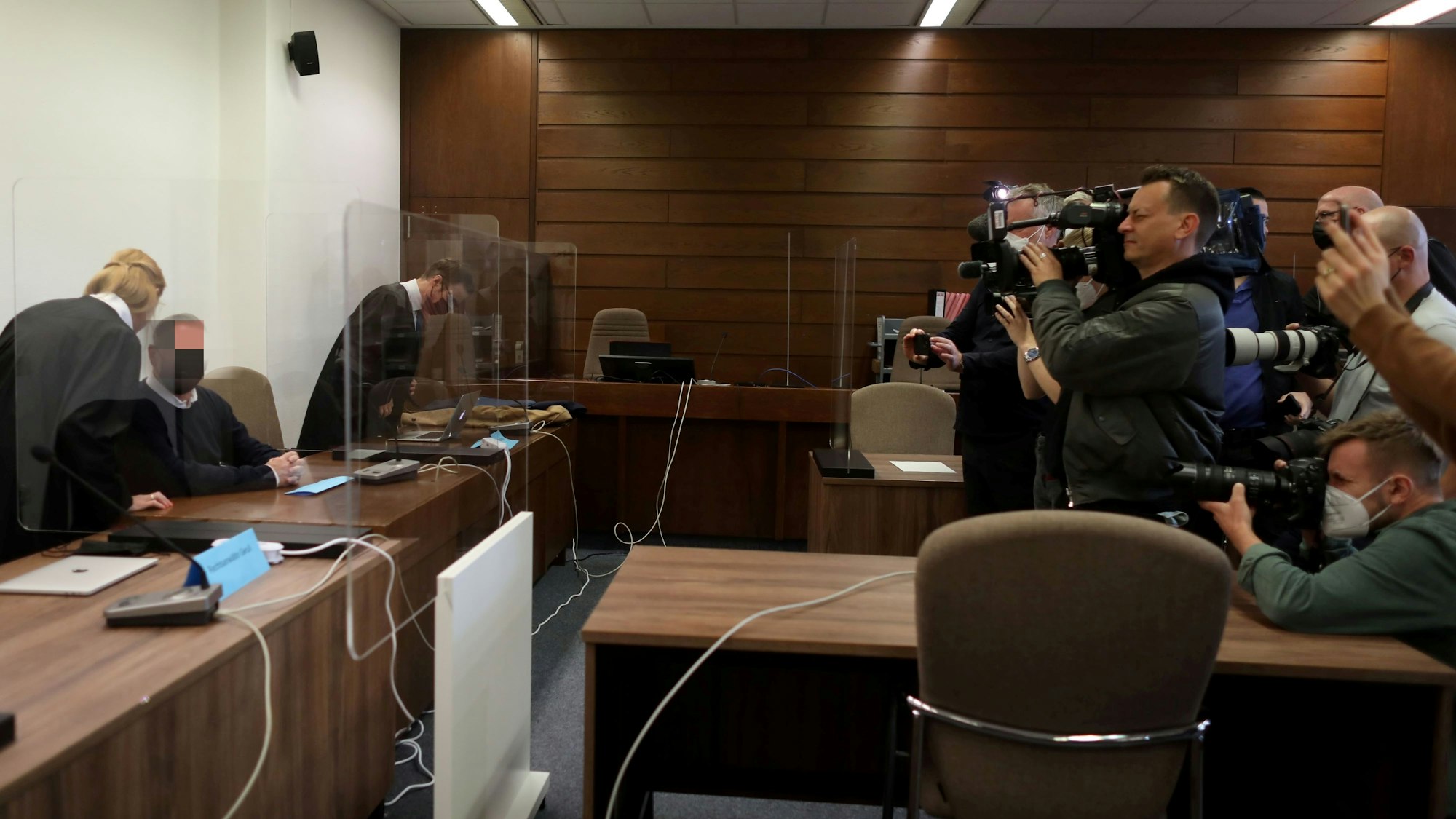 Mehrere Fotografen und Kameraleute haben ihre Kameras auf den Mann gerichtet, der auf der Anklagebank sitzt.