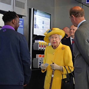 Die britische Königin Elizabeth II. (M) und Prinz Edward (r), Earl of Wessex, stehen während ihres Besuchs des Bahnhofs Paddington anlässlich der Fertigstellung des Londoner Bahnprojekts "Crossrail" neben einem Fahrkartenautomaten.