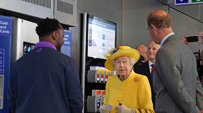 Die britische Königin Elizabeth II. (M)&nbsp;und Prinz Edward (r), Earl of Wessex, stehen während ihres Besuchs des Bahnhofs Paddington anlässlich der Fertigstellung des Londoner Bahnprojekts "Crossrail" neben einem Fahrkartenautomaten.