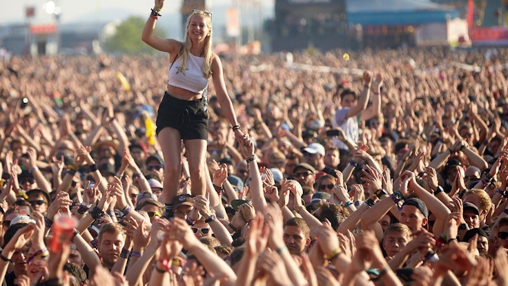 Eine junge Frau steht beim Auftritt der US-amerikanischen Punkband Rise Against vor der Hauptbühne des Musikfestival Rock am Ring auf den Schultern eines Zuschauers.