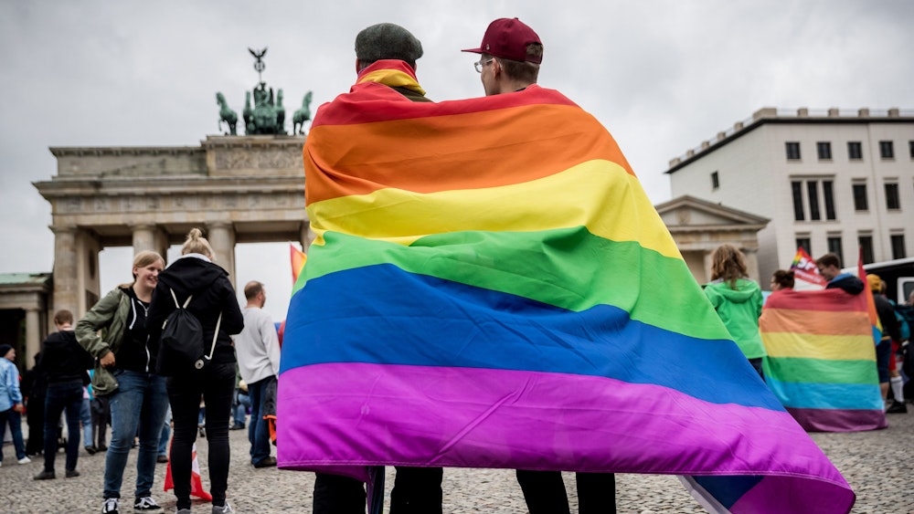 Marcel J. aus Dresden (l) und Henri V. aus Berlin stehen, gehüllt in eine Regenbogenflagge, am 30.06.2017 bei einer Veranstaltung der SPD zur Ehe für alle vor dem Brandenburger Tor in Berlin.