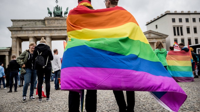 Marcel J. aus Dresden (l) und Henri V. aus Berlin stehen, gehüllt in eine Regenbogenflagge, am 30.06.2017 bei einer Veranstaltung der SPD zur Ehe für alle vor dem Brandenburger Tor in Berlin.&nbsp;