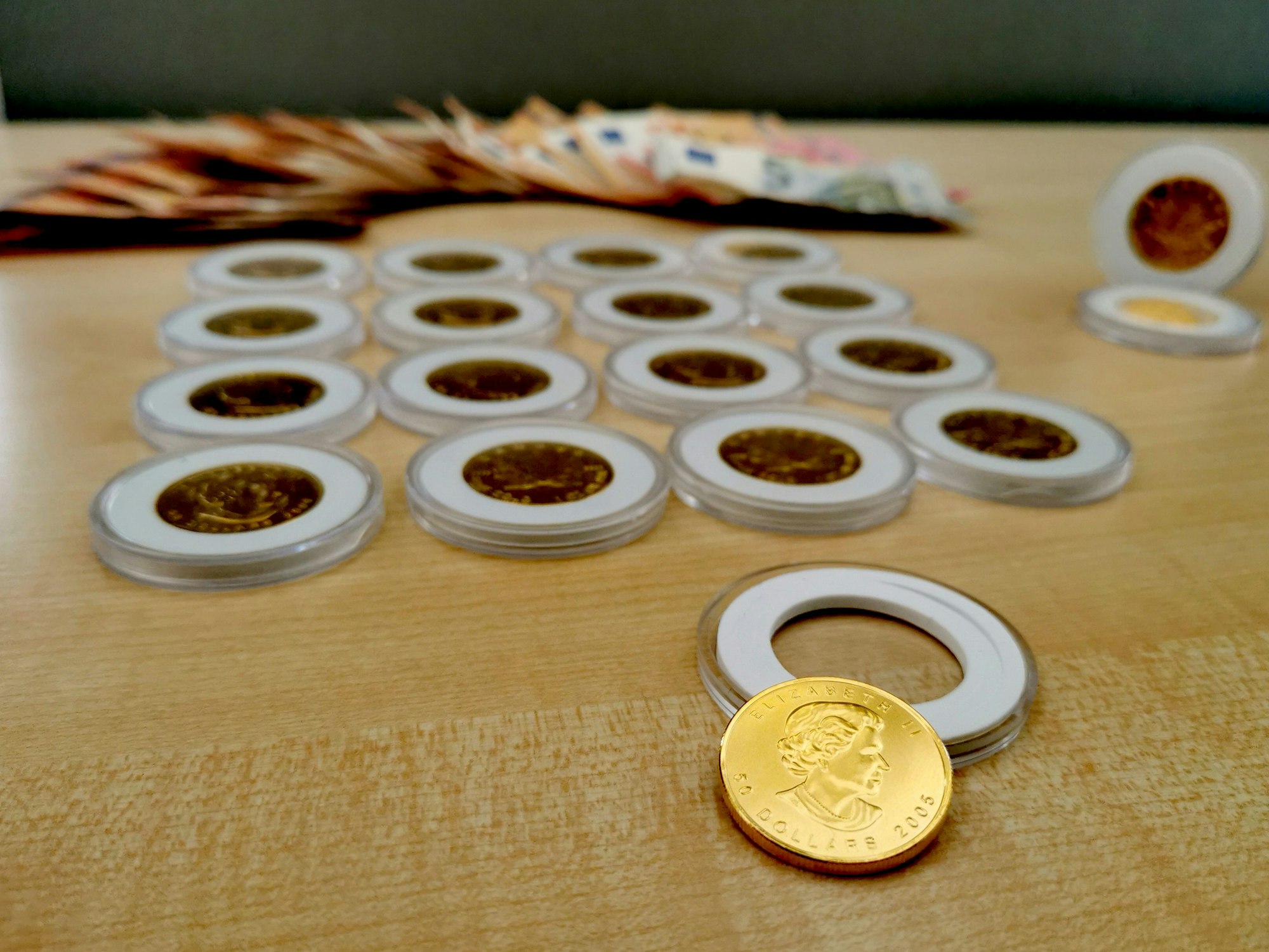 Gefälschte Goldmünzen und mehrere Hundert Euro Bargeld liegen auf einem Tisch.