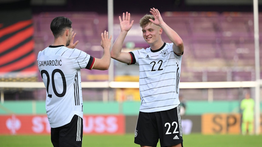 Luca Netz (re.) von Bundesligist Borussia Mönchengladbach hat sich am 3. Juni 2022 mit der Deutschen U21-Nationalmannschaft für die Europameisterschaft 2023 qualifiziert. Netz klatscht mit Lazar Samardzic ab und lächelt.