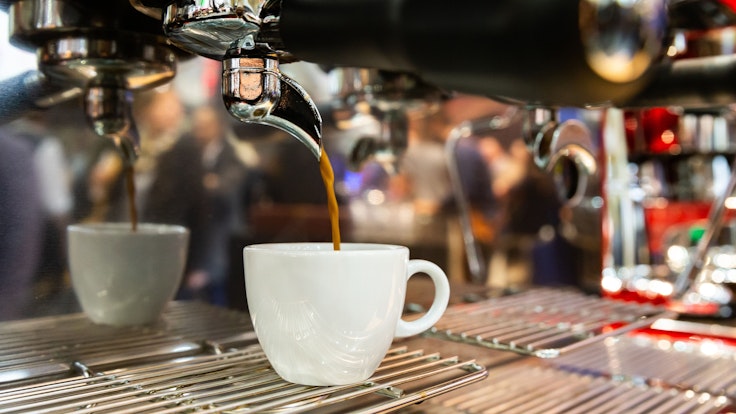Ein Espresso läuft aus einer Espressomaschine in eine Tasse.