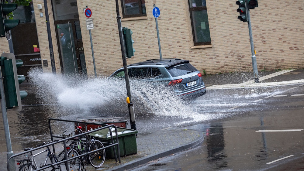 Autos fahren nach einem Starkregenschauer am Samstag (5. Juni 2022) durch das Wasser, das sich auf der Kölner Straße „Sülzgürtel“ angesammelt hat.