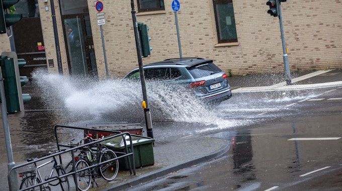 Autos fahren nach einem Starkregenschauer am Samstag (5. Juni 2022) durch das Wasser, das sich auf der Kölner Straße „Sülzgürtel“ angesammelt hat.